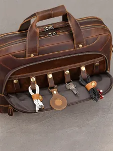 Valigetta in pelle marrone effetto vintage, con scomparti zip, manici e organizer aperto per chiavi