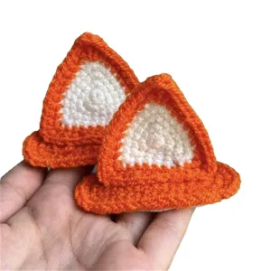 Barrettes oreilles de chat crochetées à la main, orange et blanches, présentées sur une main