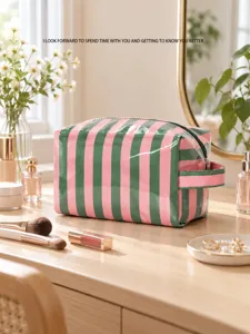 Groen-roze gestreepte toilettas met handvat op een kaptafel naast make-up en bloemen