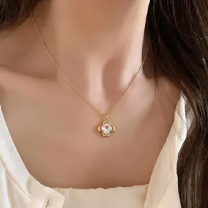 Primer plano de una cadena dorada con colgante de flor de cuatro pétalos e incrustación blanca