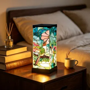 Lit stained-glass panels depict a hummingbird and pink flowers on a bedroom bedside table.