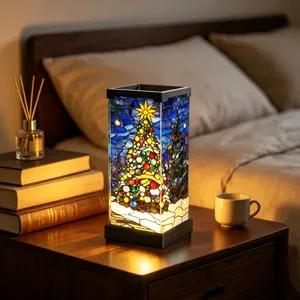 Stained-glass Christmas tree and star glowing warmly inside a black-framed bedside lamp