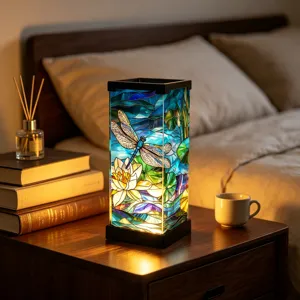 Warm-lit stained-glass lamp with dragonfly and water-lily motifs on a bedside table