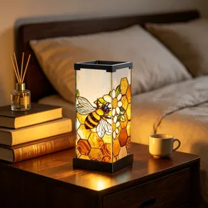 Warm bedside scene with a glowing stained-glass shade featuring a bee and honeycomb design