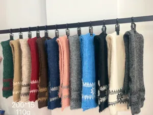 Écharpes tricotées colorées suspendues à une barre noire, avec texture douce et rayures tissées