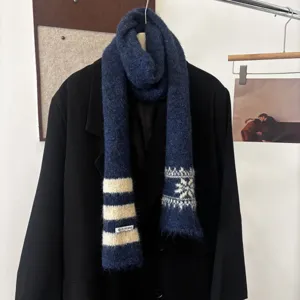 Écharpe en maille bleu marine, rayures ivoire et flocons, suspendue sur un manteau noir