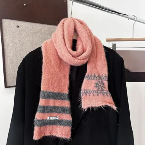 Écharpe rose en maille, à rayures grises et motifs flocons, présentée sur un manteau noir
