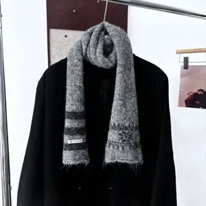 Vue d’une écharpe grise duveteuse à rayures et maille dégradée, suspendue sur un manteau noir