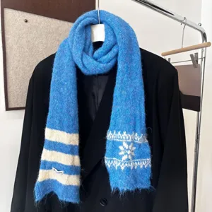 Écharpe bleue en maille, à rayures blanches et motifs flocons, drapée sur un blazer noir