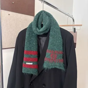 Écharpe tricotée verte à rayures rouges et motifs jacquard, drapée sur un blazer noir