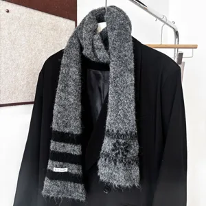 Vue rapprochée d'une écharpe en maille duveteuse à rayures grises et noires sur un blazer noir
