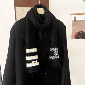 Écharpe noire en maille sur un manteau, avec rayures blanches, motifs flocons et franges aux bouts