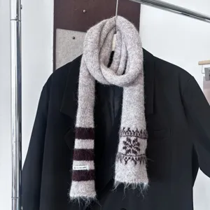 Écharpe en maille douce, à rayures brunes, motifs jacquard et franges, posée sur un blazer noir