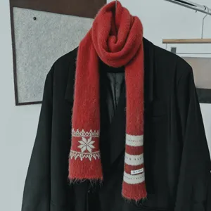 Écharpe rouge sur manteau noir, motifs blancs de flocons et rayures, avec extrémités frangées