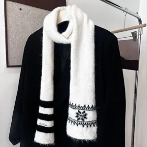 Écharpe blanche en maille duveteuse sur un manteau noir, avec motifs noirs de flocons et rayures