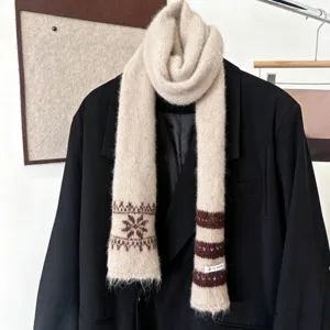 Écharpe en maille crème à motifs de flocons bruns et rayures, posée sur un blazer noir