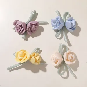 Vier Rosenblüten aus Satin in Lila, Blau, Gelb und Elfenbein, jeweils mit hellgrüner Schleife