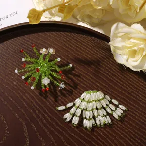 Handwoven green bead sprays with red accents and white flowers beside a pearl-bead fan tassel