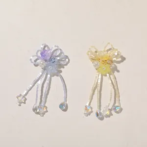 Beaded bow ornaments with dangling strands, crystal accents and floral details on a pale background