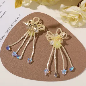 Close-up of cream bead flower earrings with yellow resin blooms, pearls and blue crystal drops
