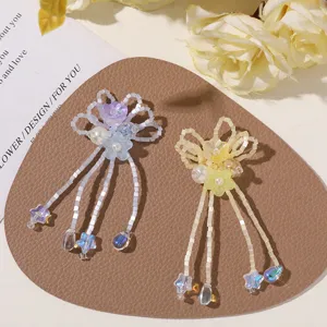 Overhead view of two beaded floral designs with pearls and dangling star and teardrop charms