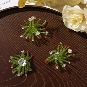 Three green beaded starburst ornaments with red and white accents arranged on a dark wooden tray