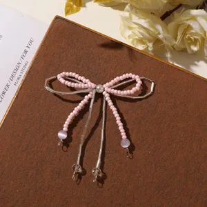 Primo piano di un fiocco rosa di perline, con centro perlato, tubi argentati e pendenti viola