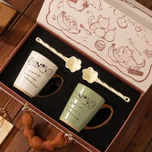 Zwei Keramik-Katzenbecher in Creme und Grün mit Löffeln in einer Vintage-Geschenkbox