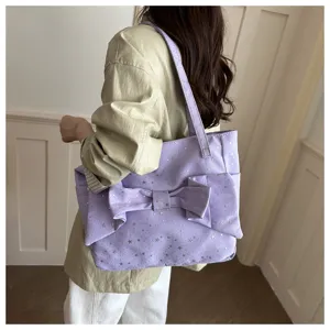 Borsa lilla con motivo a stelle e grande fiocco, portata a spalla in un ambiente interno