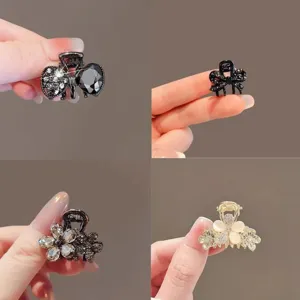 Four small jeweled hair clips shown in hand: black bow and flower styles, plus a gold pearl flower.