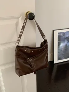 Borsa marrone effetto pelle appesa alla porta, con borchie, occhielli e laccio con nappa