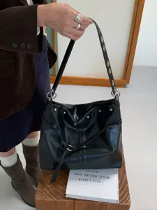 Borsa nera in similpelle tenuta in mano, con coulisse, occhielli argentati e dettagli ad anello