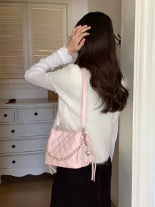 Back view of a woman carrying a pink quilted bucket bag with a chain strap and pearl heart charm