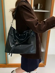 Borsa nera in similpelle a spalla, con borchie, laccio pendente e anelli metallici