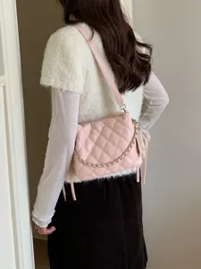 Model wearing a pink quilted bag with a silver chain and pearl tassel, viewed from the side