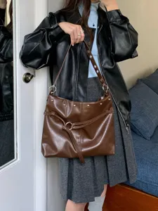 Borsa marrone in similpelle, con borchie argentate, anelli metallici e cinturino frontale annodato