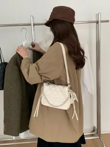 Rear view of a woman carrying a cream quilted mini bag with silver chain and pearl charm