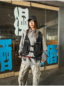 View of a black utility vest with zip pockets and adjustable straps, layered over a gray sweatshirt
