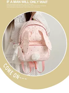 Sac rose à pois porté, avec oreilles de lapin, pompon doux, nœud perlé et breloques en dentelle