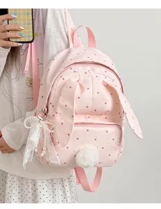 Sac à dos rose à pois porté par un modèle, avec oreilles de lapin, breloque perlée et pompon doux