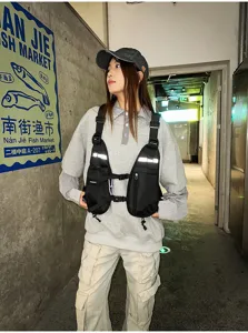 Street-style view of a black utility chest rig with reflective strips, pockets and adjustable straps