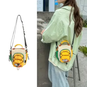 Petit sac bandoulière colorblock porté dehors, avec poche avant à cordon et sangle réglable