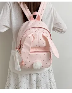 Vue arrière d’un sac rose pâle à pois, avec oreilles de lapin, poches zippées et pompon doux.
