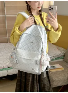 Selfie dans le miroir montrant un sac à dos bleu clair à carreaux, poche à pois et pendentif lapin