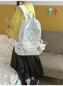 Vue arrière d’un modèle assis portant un sac à dos bleu clair à carreaux, à pois, avec un lapin