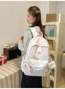 Vue d’une femme portant un sac à dos rose et blanc, à carreaux et pois, avec de petits accessoires