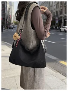 Vue urbaine d’une femme portant un sac souple noir à l’épaule avec un pendentif ourson