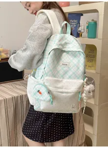Sac vert menthe à carreaux et pois porté par un modèle, avec breloques lapin et pochette carotte