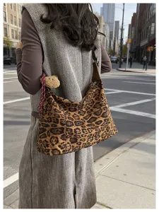 Vue de rue d’un sac souple brun à imprimé léopard, en aspect daim et forme de croissant