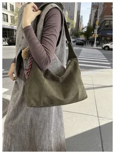 Sac effet daim vert olive porté à l’épaule dans une rue urbaine près d’un passage piéton